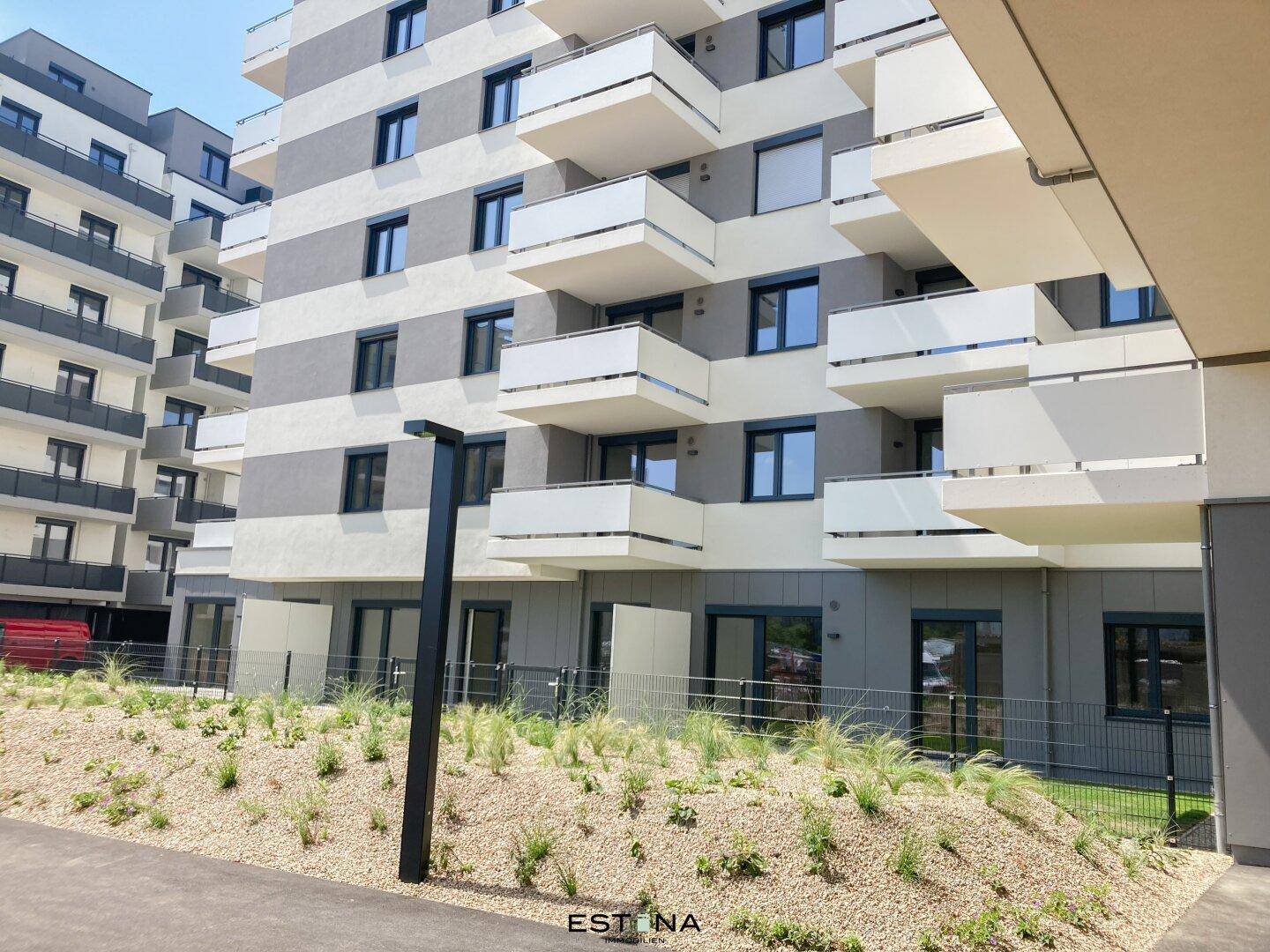 Ansicht eines modernen Wohngebäudes mit Balkonen und begrüntem Außenbereich.