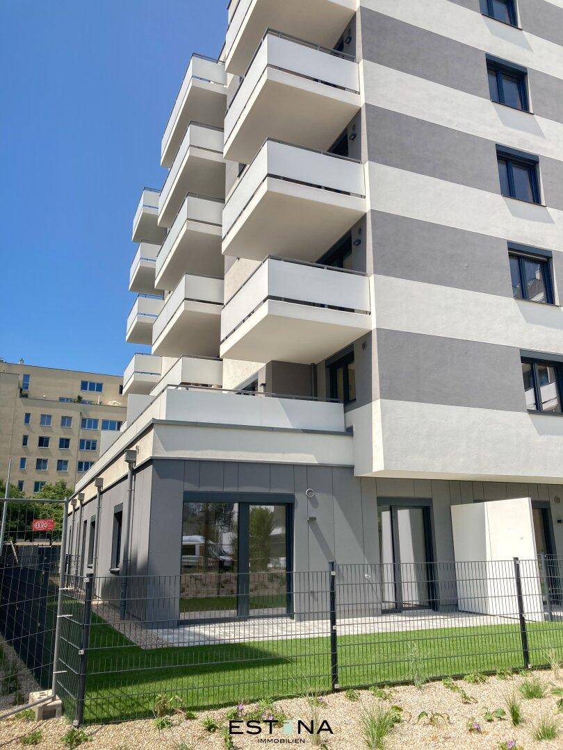 Erdgeschosswohnung mit privatem Gartenbereich und Blick auf die moderne Fassade.