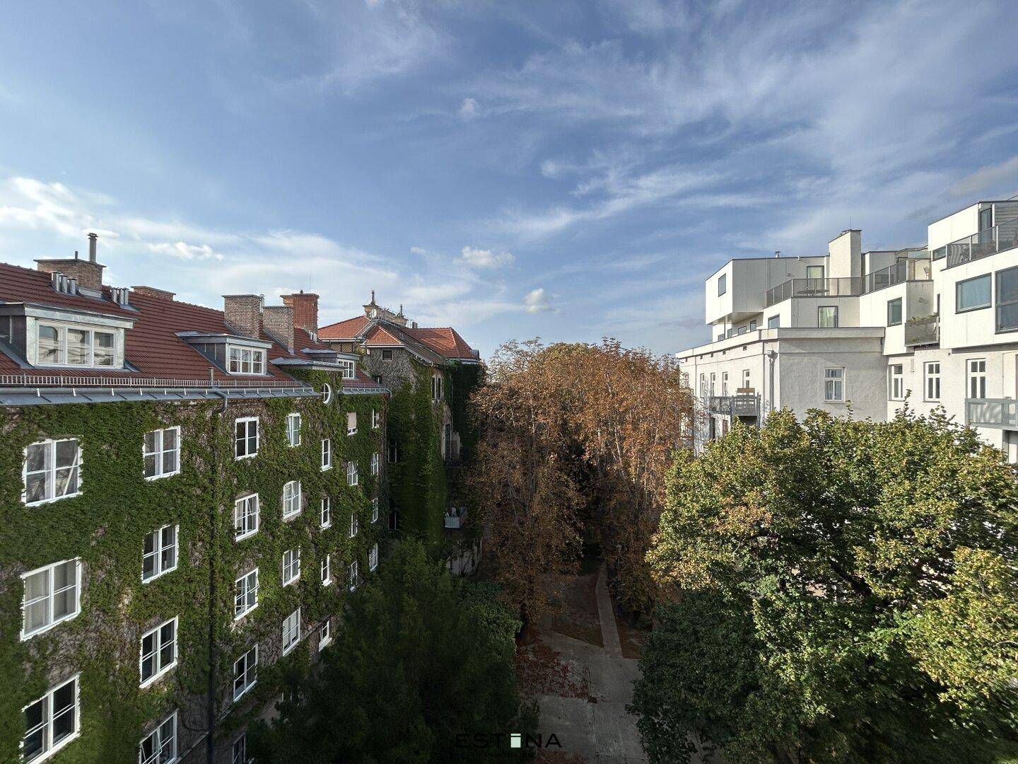 Blick auf begrünte Fassaden und umliegende Gebäude unter blauem Himmel.