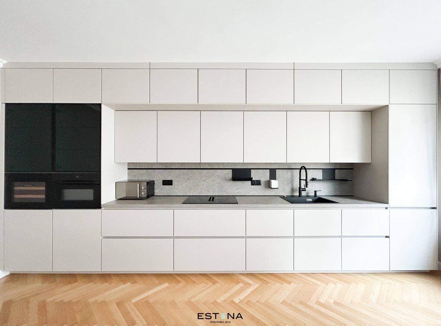 Elegante, minimalistische Küche mit integrierten Geräten, Mikrowelle und dunkler Spüle.