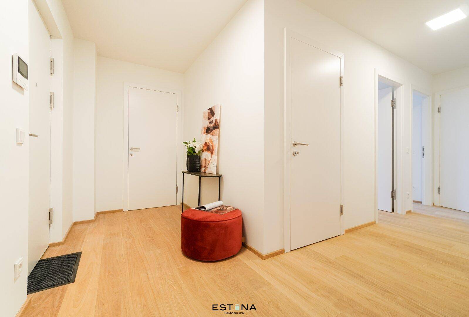 Heller Eingangsbereich mit Holzboden und modernen weißen Türen, einladend und funktional.