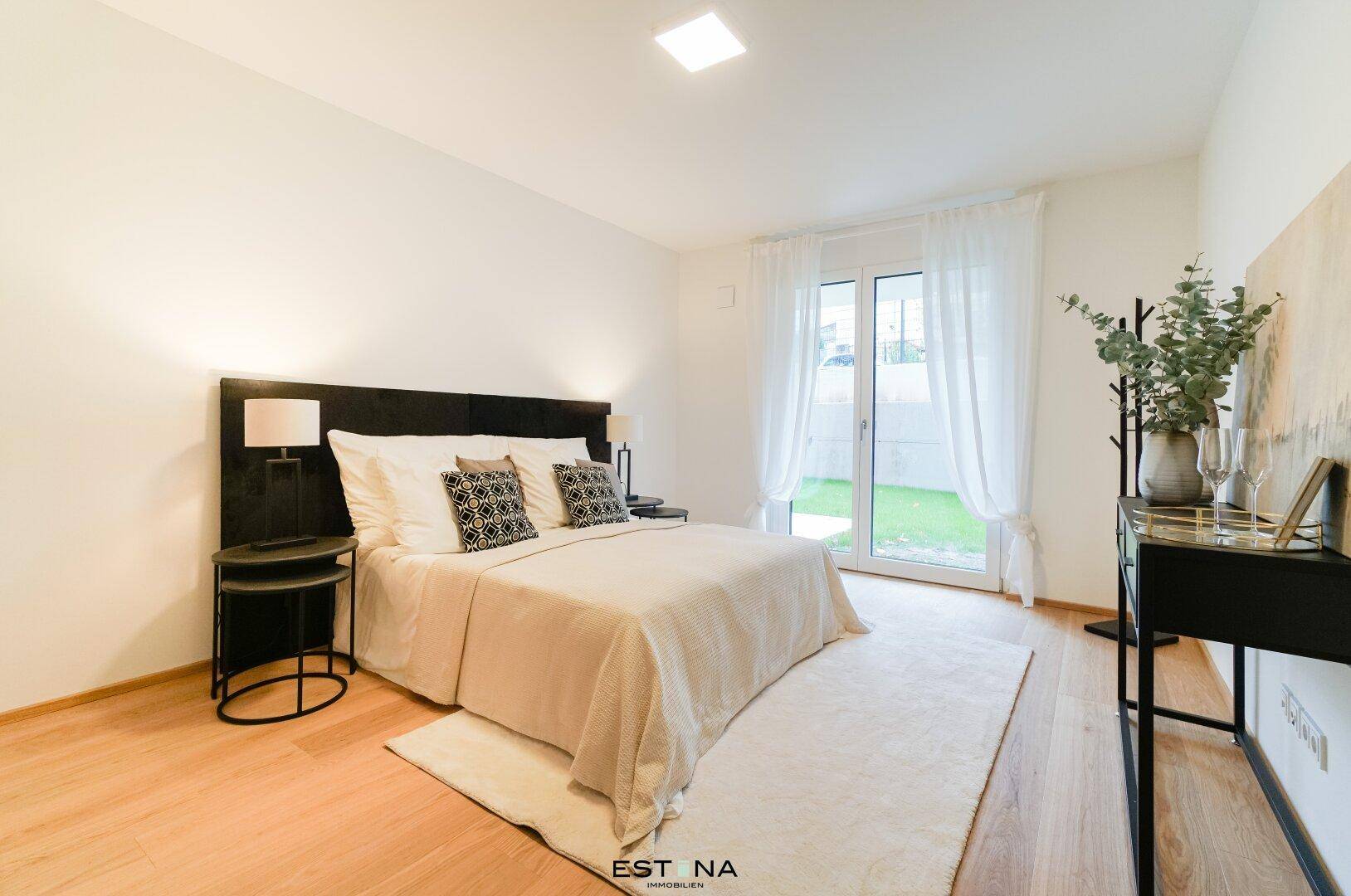 Helles Schlafzimmer mit Zugang zum Garten und modernem Doppelbett in minimalistischem Design.
