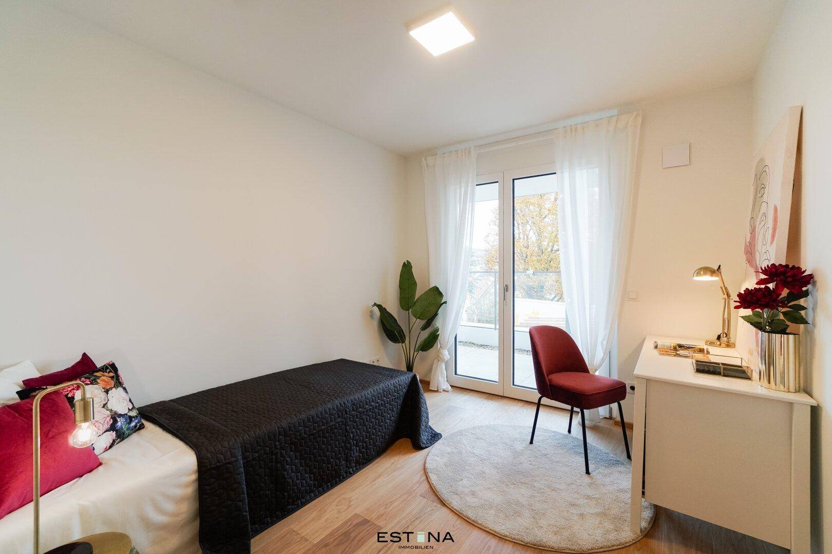 Helles Zimmer mit Holzboden, Schreibtisch und Zugang zum Balkon, ideal als Kinder- oder Arbeitszimmer.