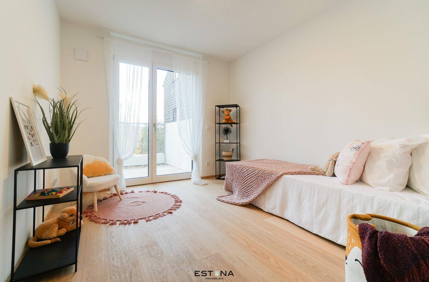 Freundliches Kinderzimmer mit Holzboden, Tagesbett und Zugang zum Balkon, hell und einladend.
