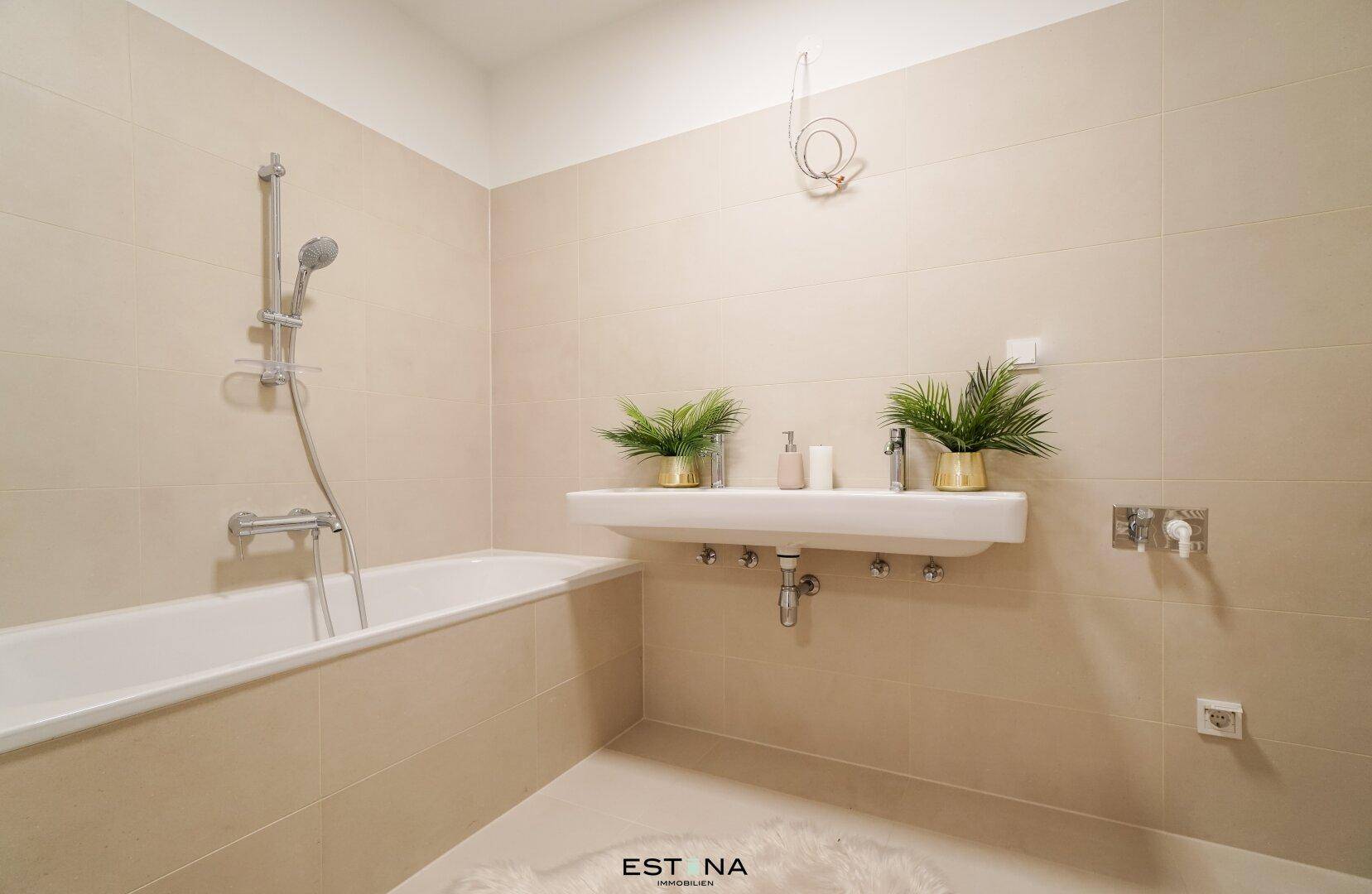 Modernes Badezimmer mit Badewanne, Waschbecken und beigen Wandfliesen für entspannende Momente.