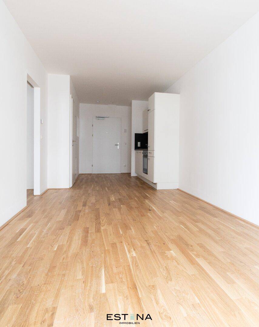 Heller Wohnbereich mit neuem Parkettboden und integrierter Küchenzeile in modernem Design.