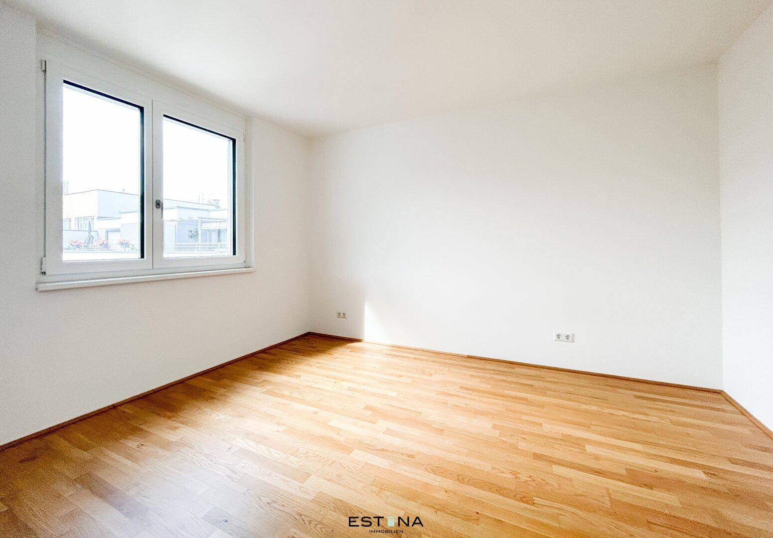 Leeres Zimmer mit großen Fenstern und hellem Parkettboden, ideal als Schlafzimmer.