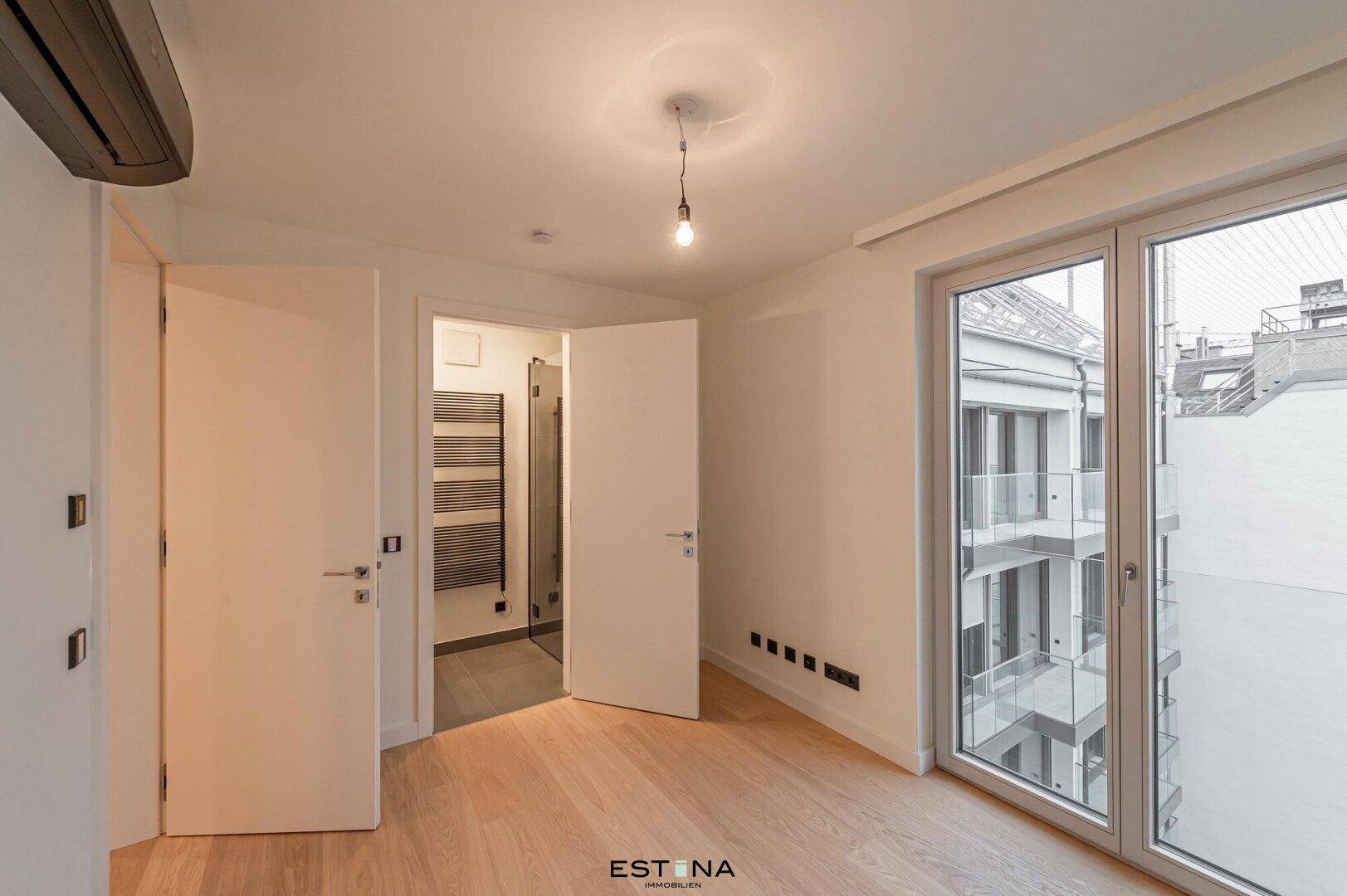Modernes Schlafzimmer mit Parkettboden und direktem Zugang zum Badezimmer.