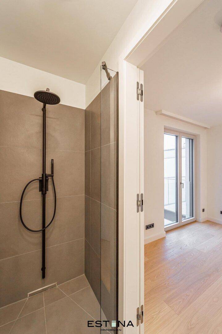 Moderne Dusche mit Regenduschkopf und dunklen Armaturen in einem eleganten Bad.