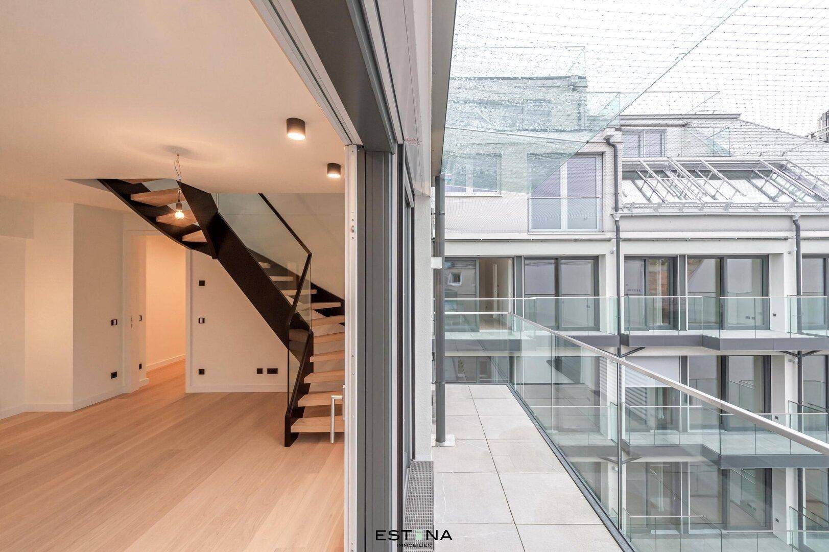 Heller Innenraum mit großen Schiebetüren, die auf eine moderne Terrasse führen.