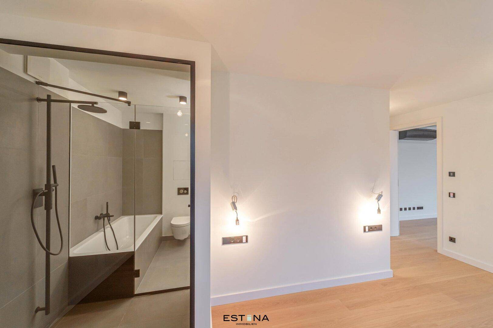 Modernes Badezimmer mit Badewanne, Dusche und eleganten grauen Fliesen.
