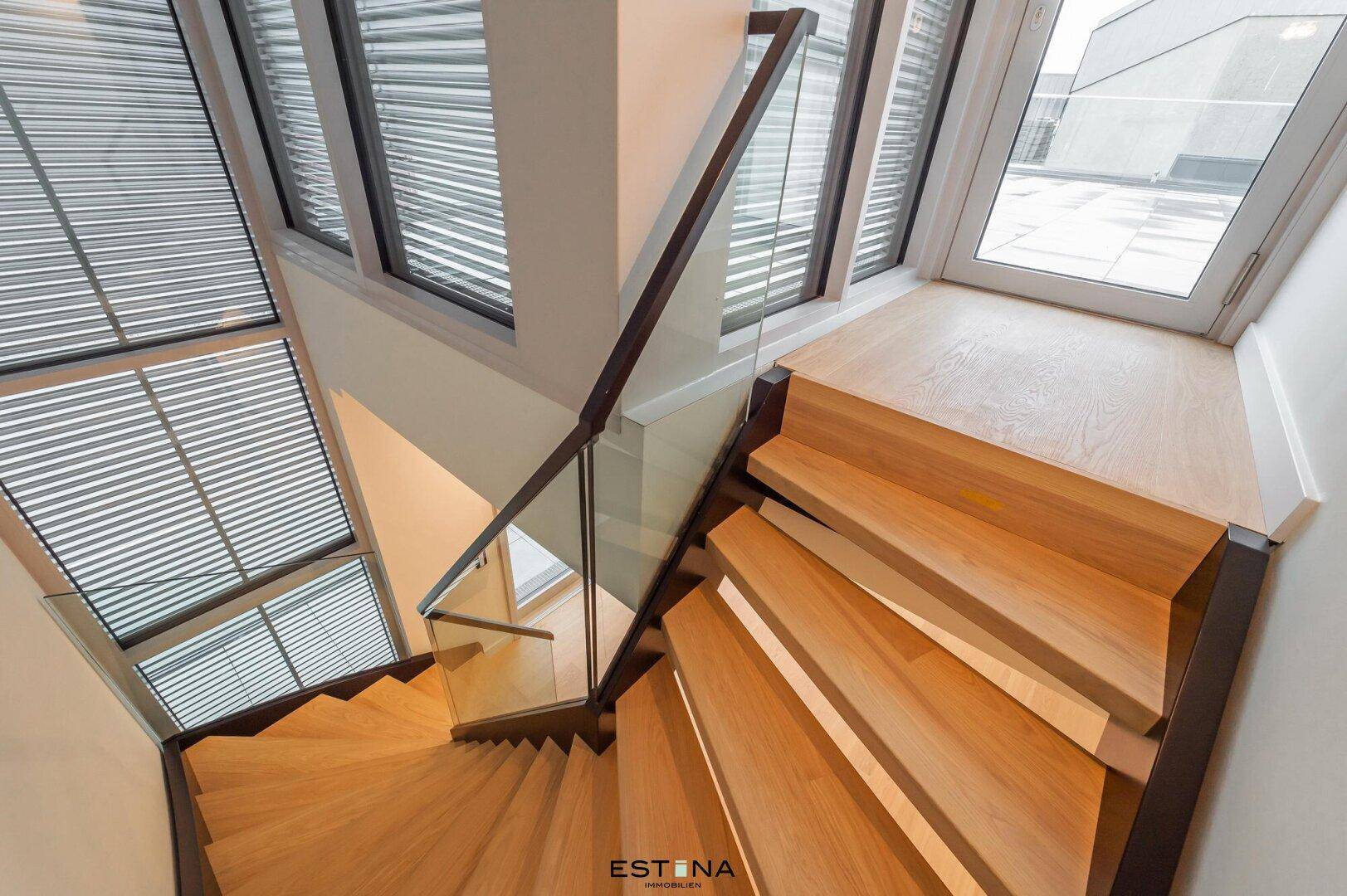 Elegante Holztreppe mit Glasgeländer, die die Etagen verbindet.