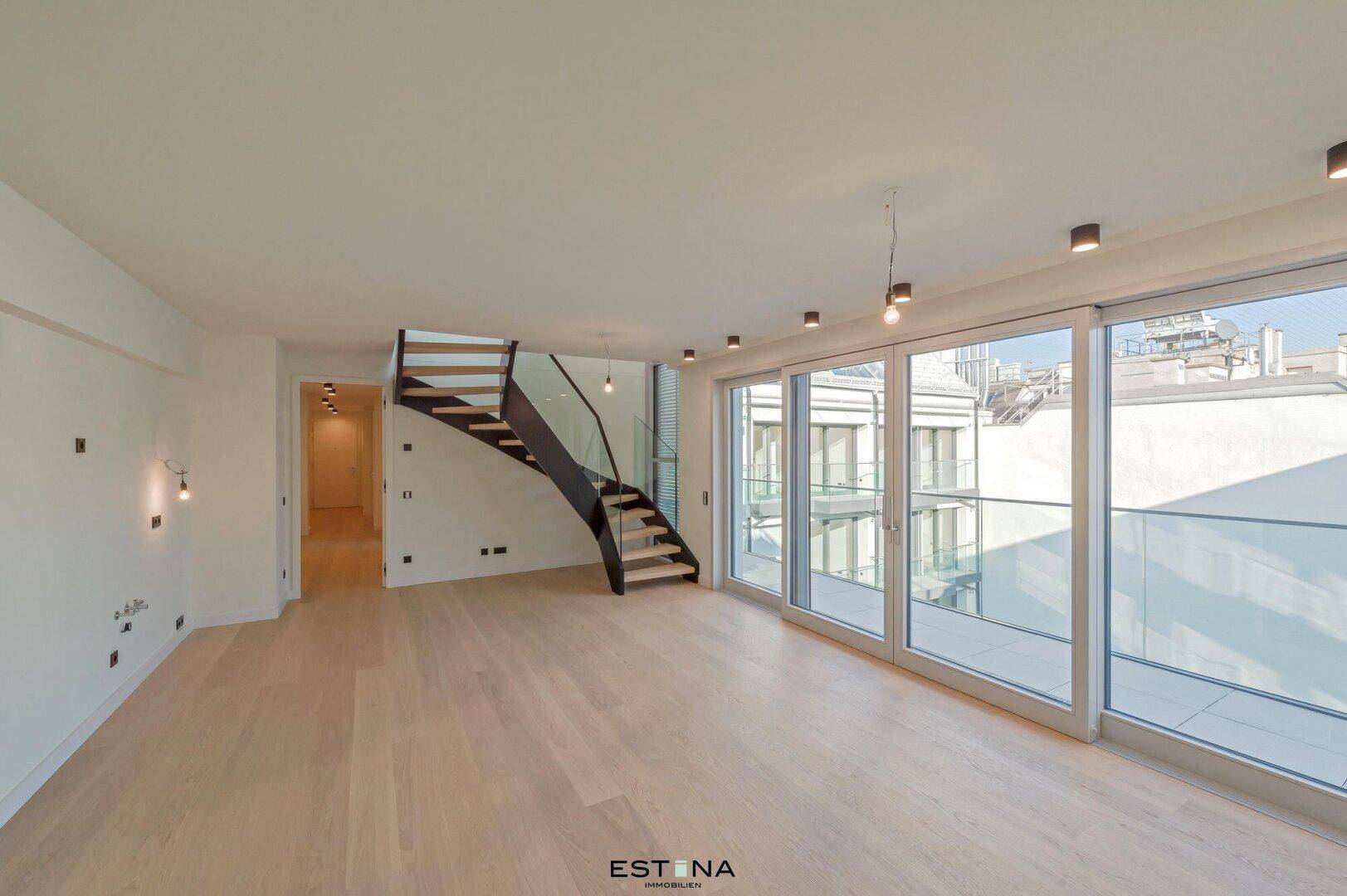 Helles Wohnzimmer mit Holzparkettboden, großen Fenstern und moderner Treppe.