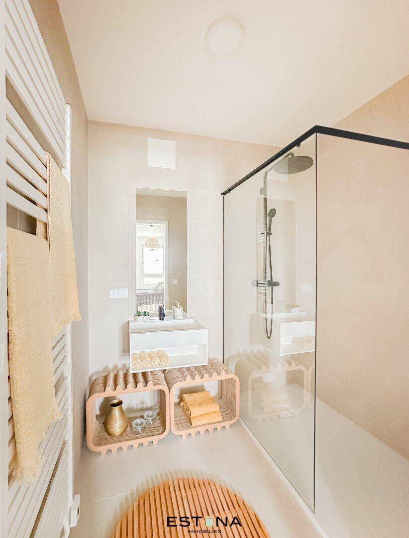 Modernes Badezimmer mit ebenerdiger Dusche, Einzelwaschbecken und beheiztem Handtuchhalter.