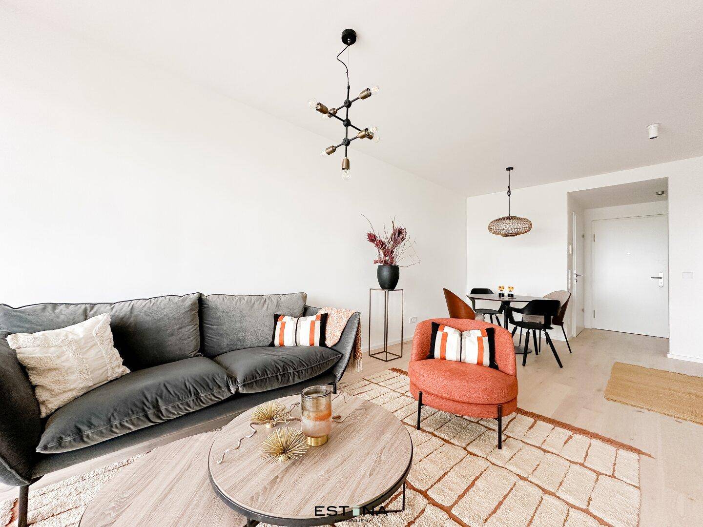Gemütlicher Wohnbereich mit modernem Sofa, Sessel und stilvollem Couchtisch in hellen Farben.