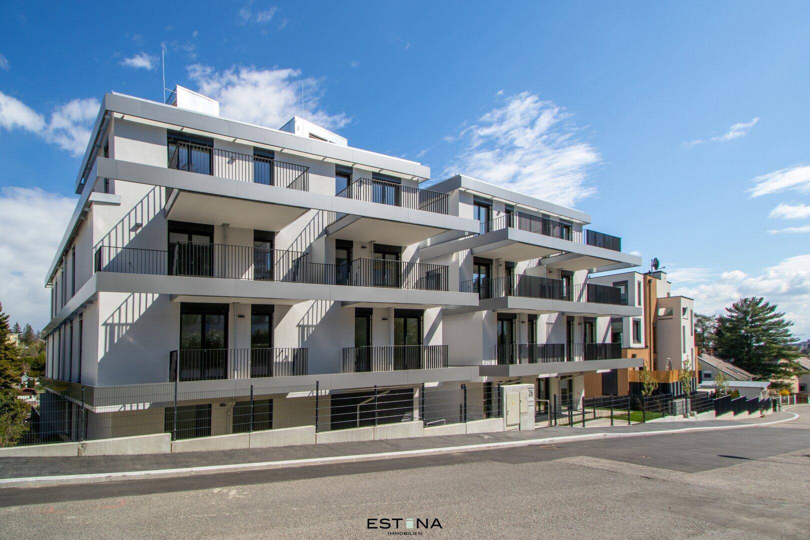Ansicht eines modernen Wohnkomplexes mit mehreren Balkonen und klaren Linien.