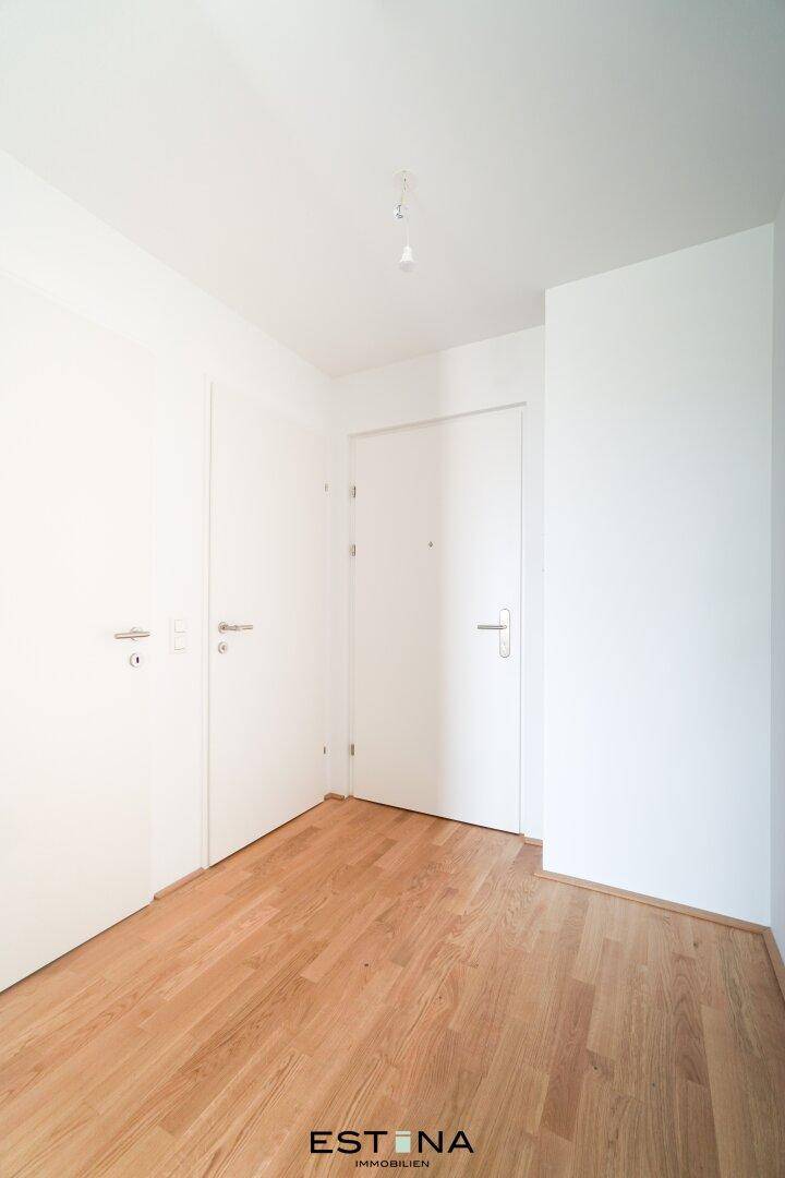Heller Flurbereich mit Holzboden und mehreren weißen Türen, bietet Zugang zu verschiedenen Räumen.