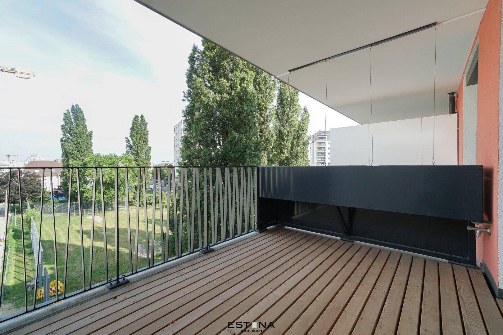 Geräumiger Balkon mit Holzboden und Blick ins Grüne, ideal zum Entspannen im Freien.
