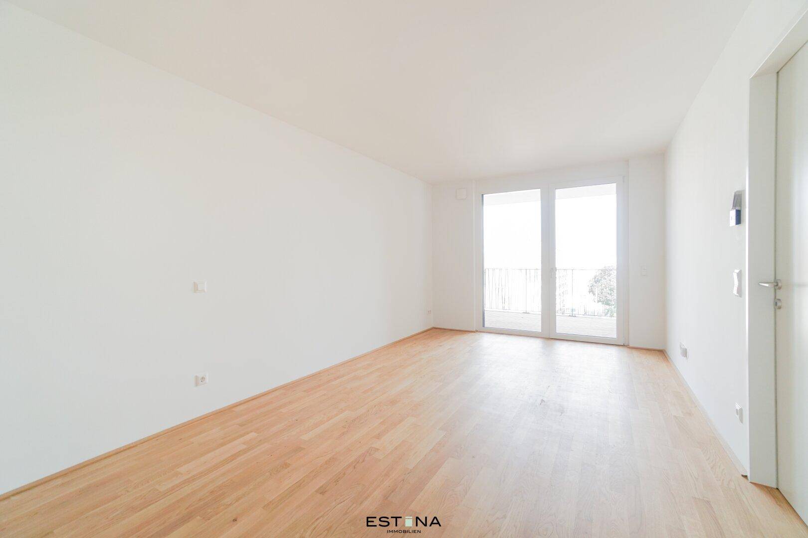 Lichtdurchfluteter Raum mit Holzboden und französischem Balkon, bietet viel natürliches Licht.