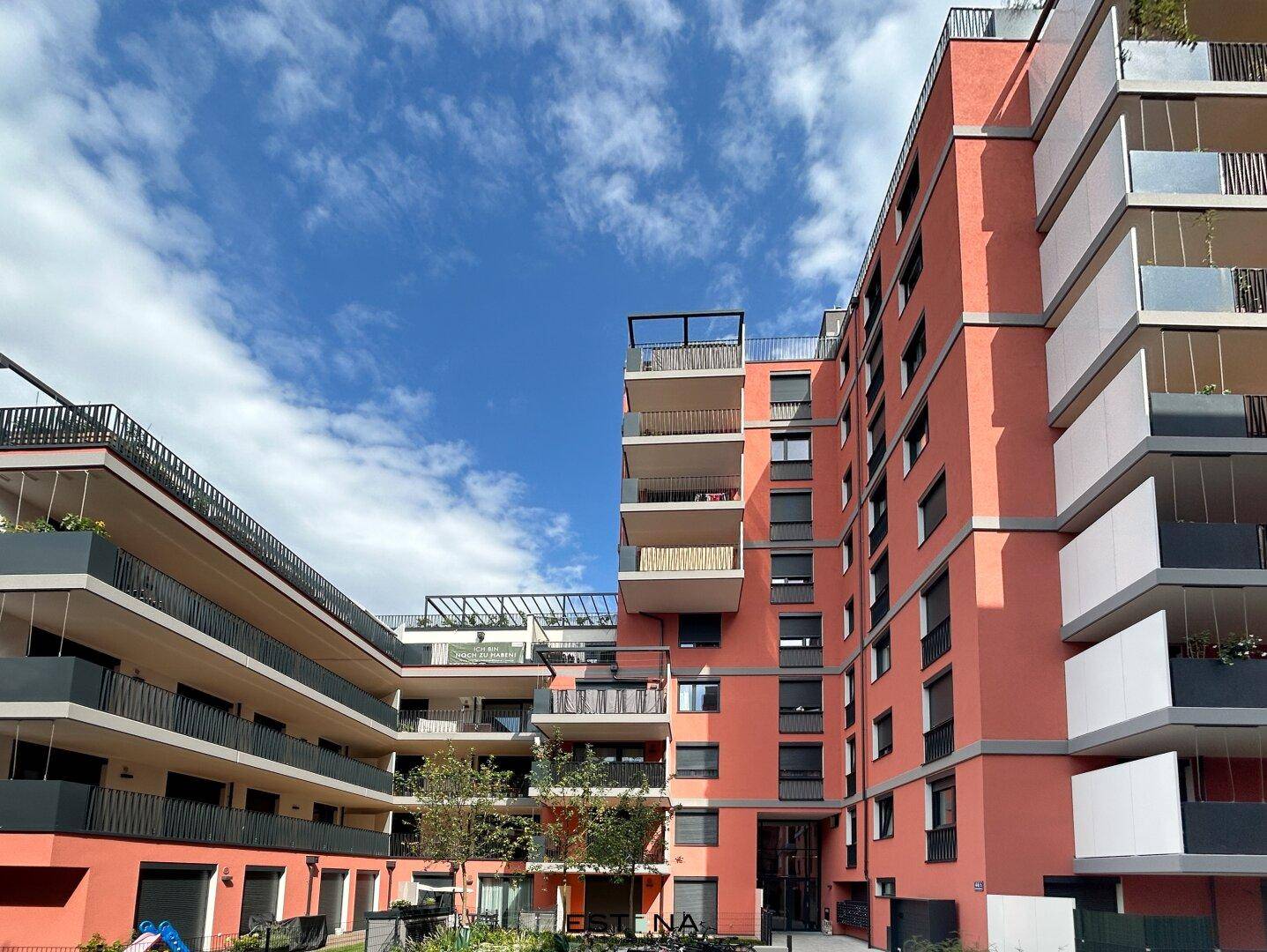 Ansicht des Innenhofs eines Wohnkomplexes mit moderner Architektur, Balkonen und gepflegten Grünflächen.
