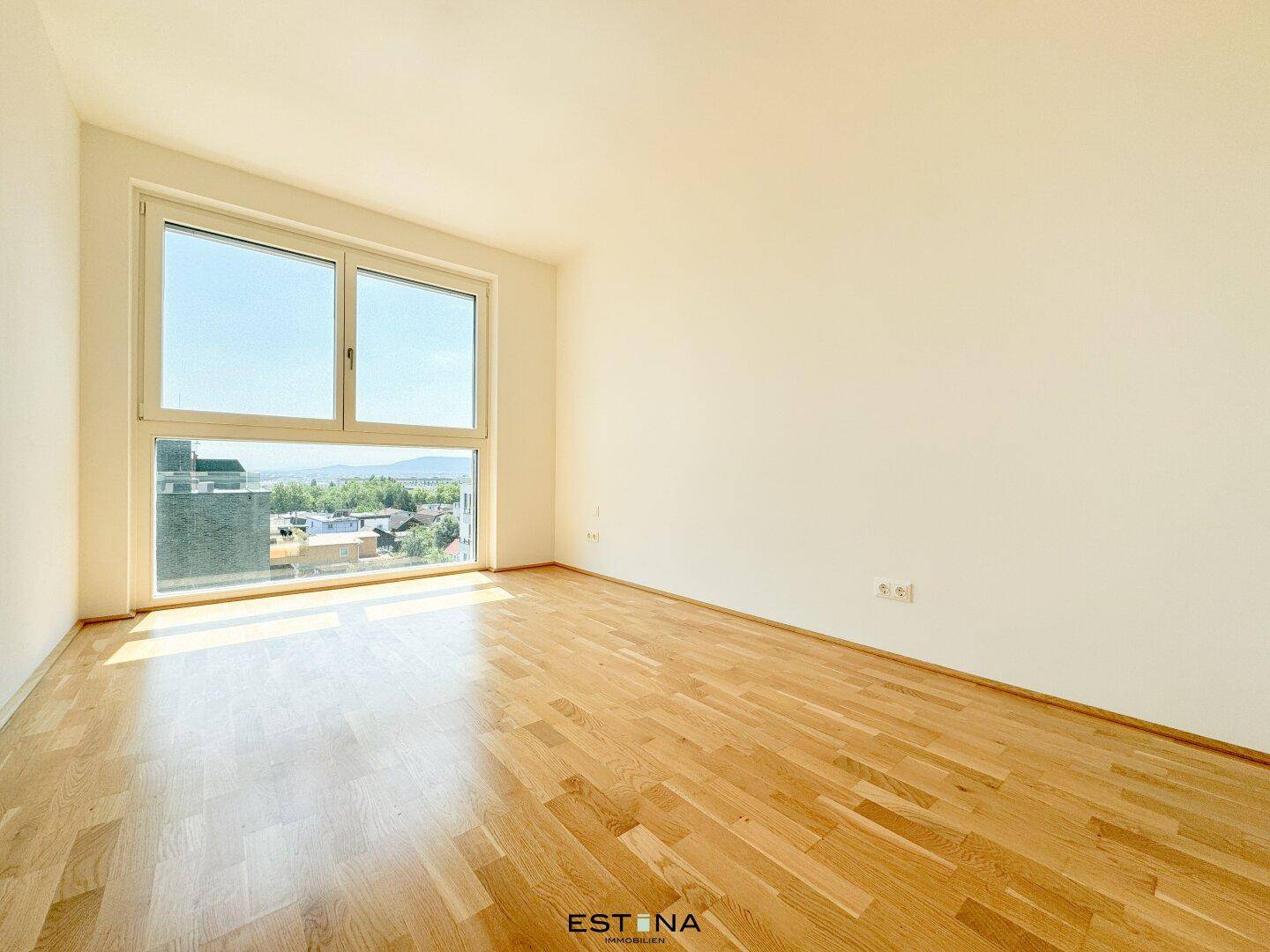Helles Schlafzimmer mit großen Fenstern und Parkettboden, bietet einen weiten Blick.