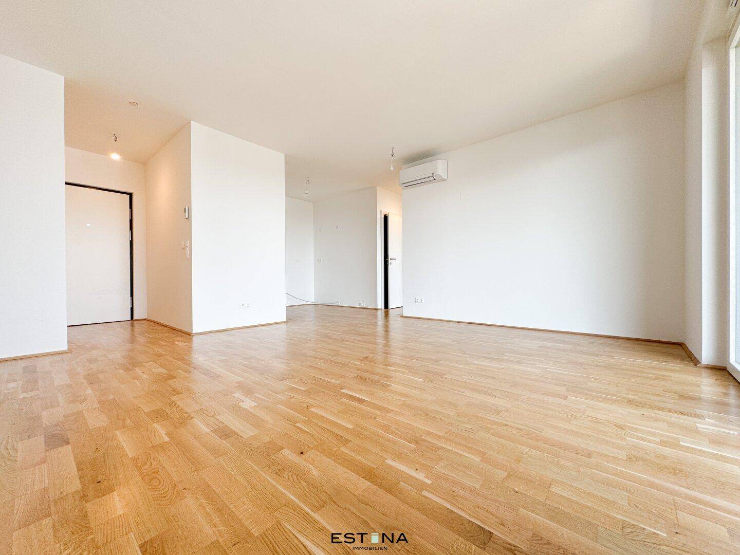 Helles, leeres Zimmer mit Parkettboden und weißen Wänden, bereit zur individuellen Gestaltung.