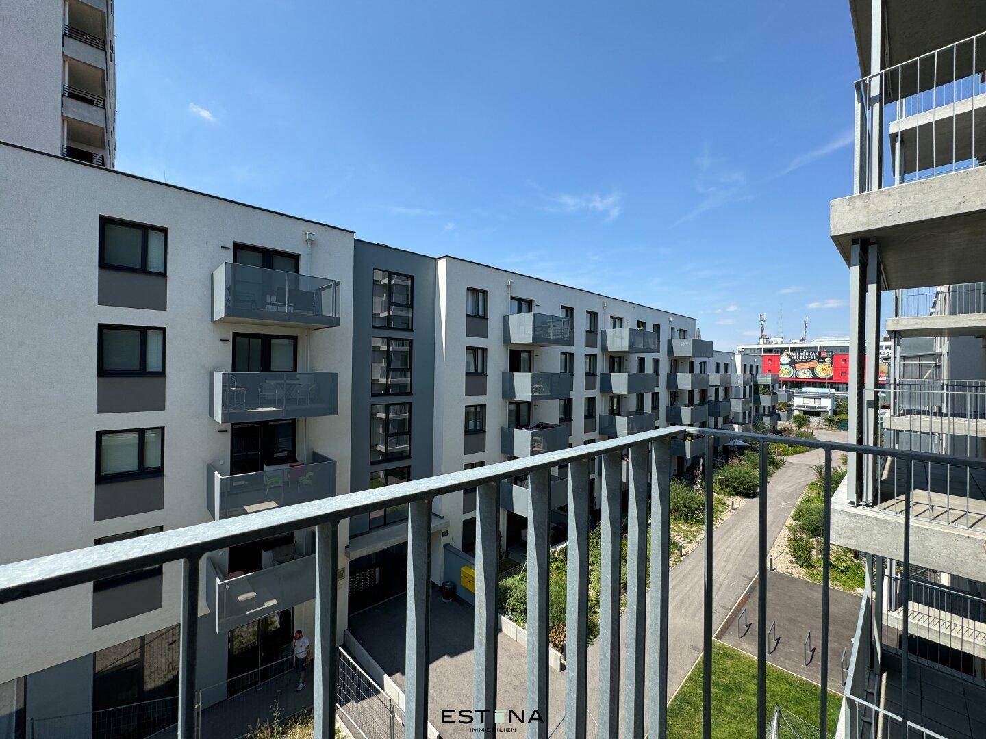 Moderne Wohnanlage mit mehreren Balkonen und gepflegten Außenbereichen unter blauem Himmel.
