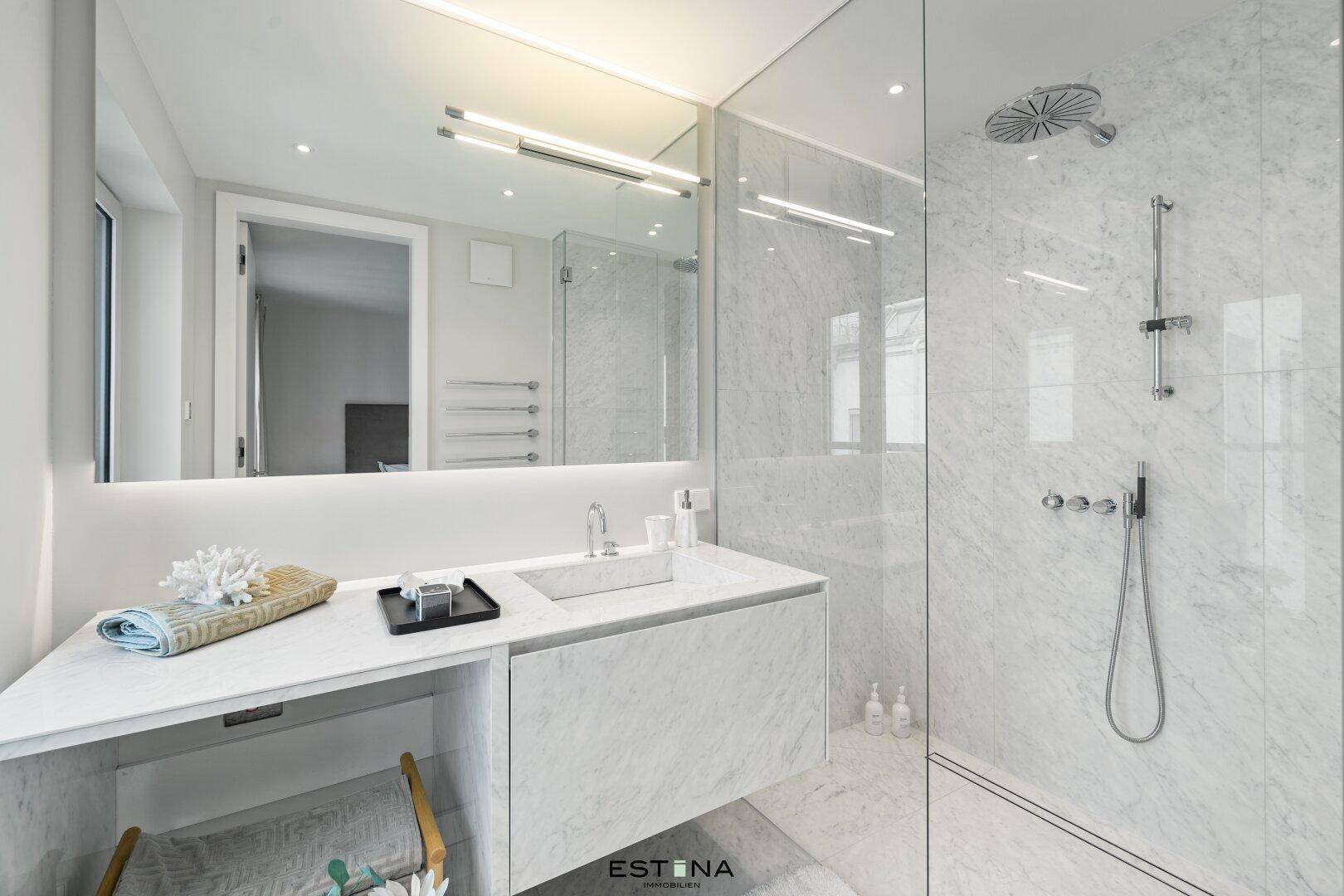 Luxuriöses Badezimmer mit Marmorfliesen, begehbarer Dusche und modernem Einzelwaschbecken.