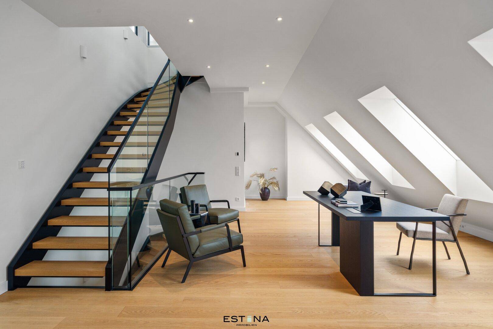 Moderner Arbeitsbereich mit Holzboden, schräger Decke und eleganter Treppe mit Glasgeländer.