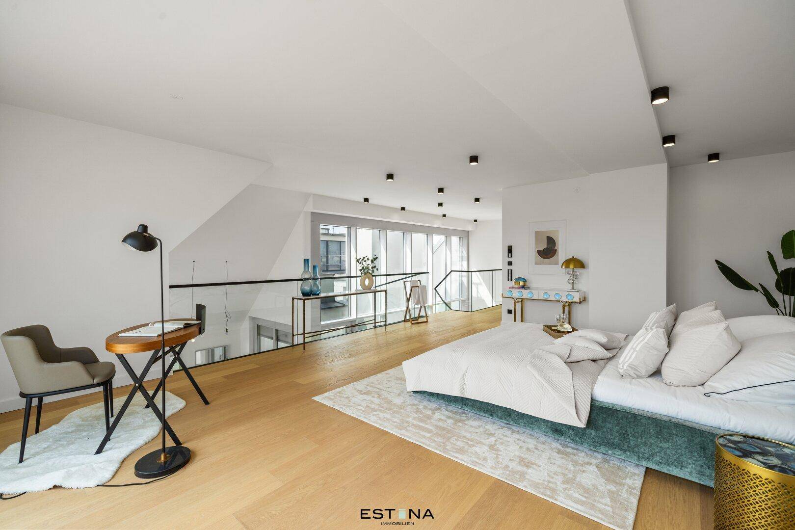 Offenes Schlafzimmer mit Holzboden und Blick auf die Galerieebene mit Glasgeländer.