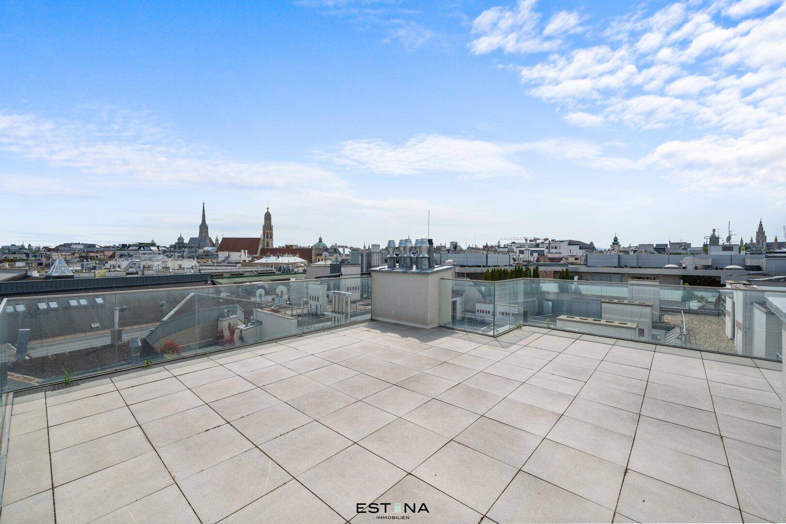 Weitläufige Dachterrasse mit Fliesenboden und beeindruckendem Panoramablick über die Stadt.