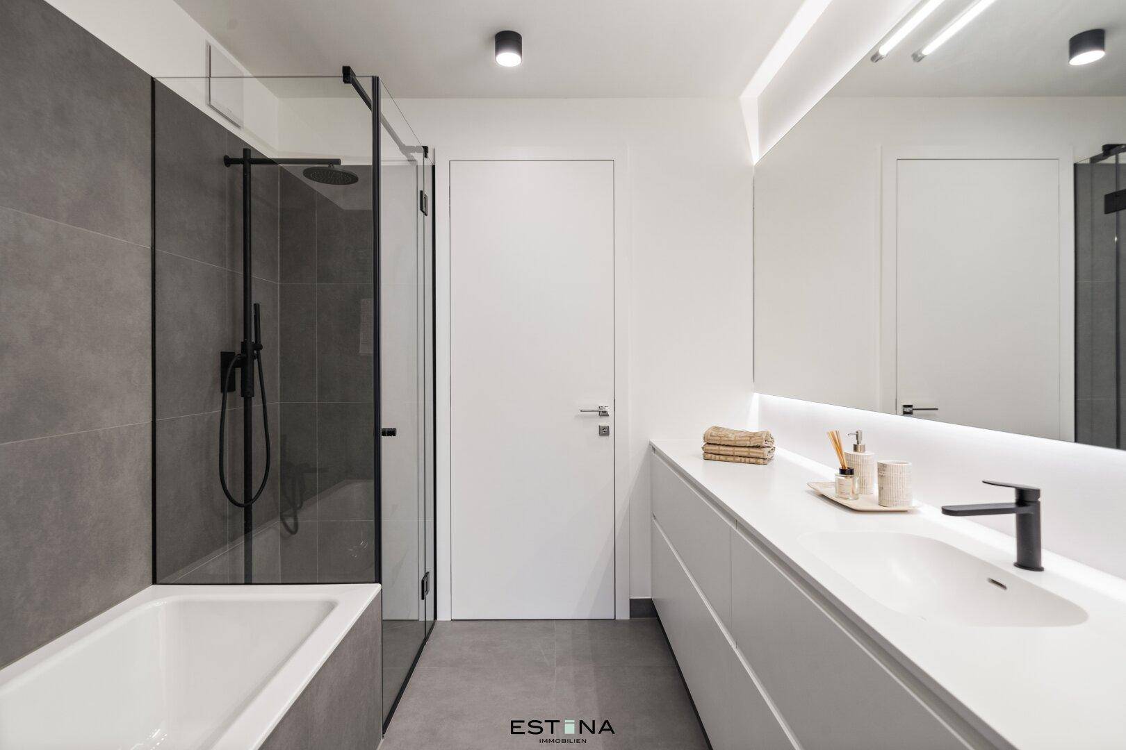 Modernes Badezimmer mit Badewanne, begehbarer Dusche, Doppelwaschbecken und grauen Fliesen.