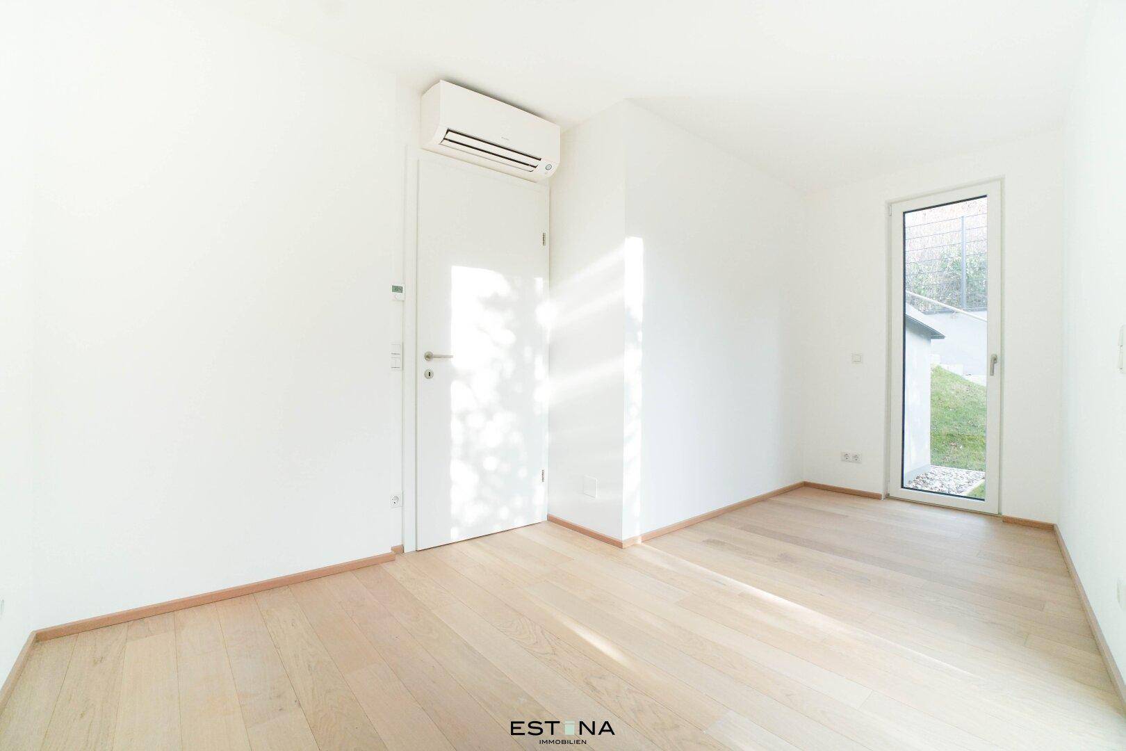 Helles Schlafzimmer mit Parkettboden, Klimaanlage und direktem Zugang zum Außenbereich.