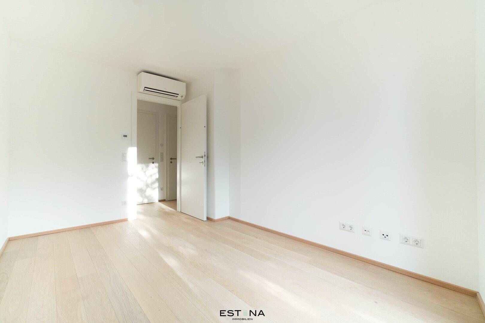 Helles Schlafzimmer mit Parkettboden und Klimaanlage, bereit für individuelle Gestaltung.