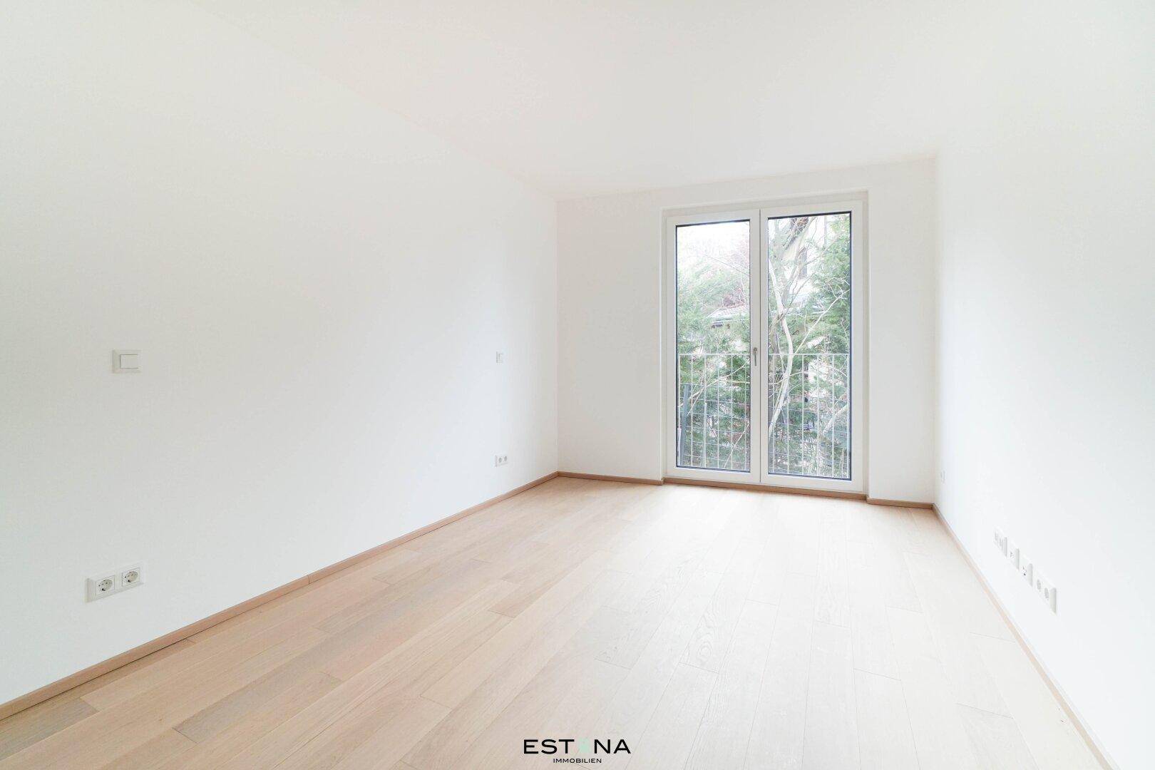 Freundliches Schlafzimmer mit hellem Parkettboden und großem Fenster, das viel Licht hereinlässt.
