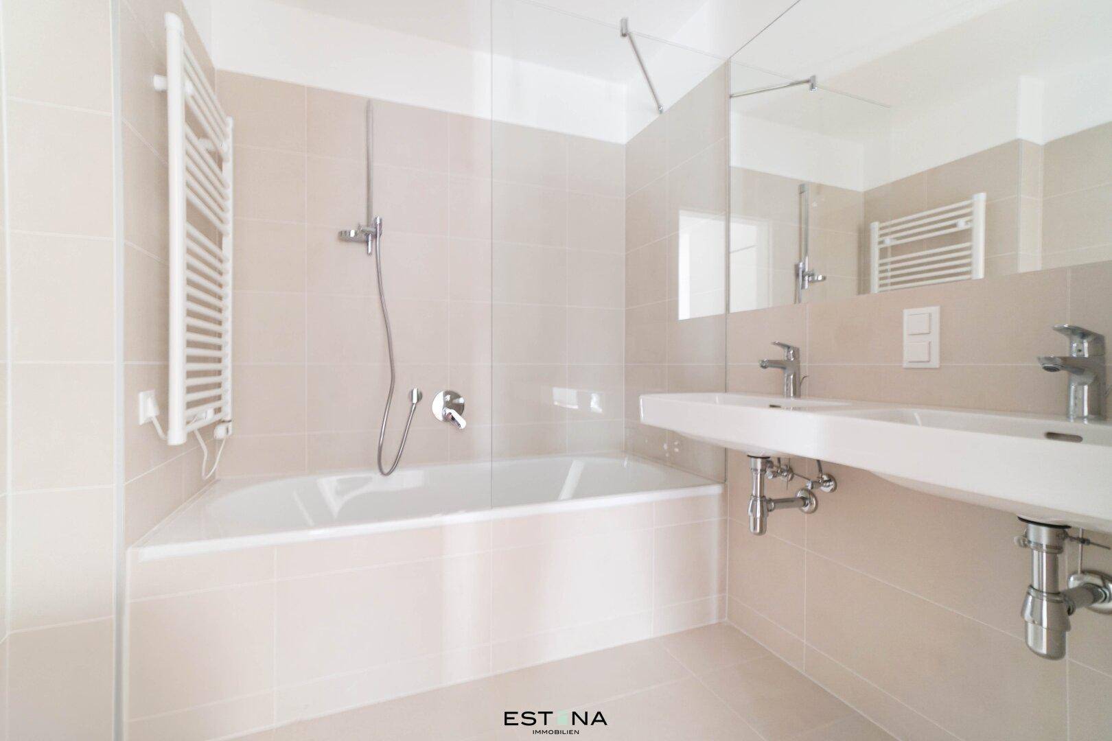 Modernes Badezimmer mit Badewanne, Doppelwaschbecken und hellen Fliesen.
