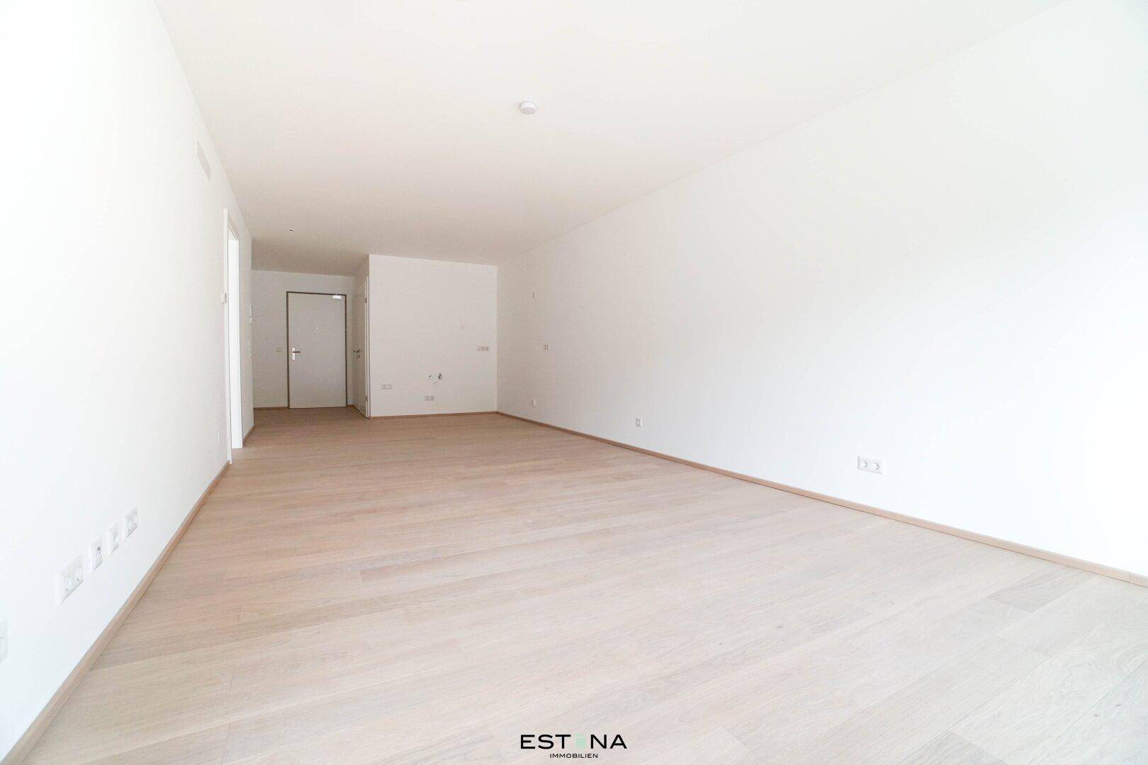 Heller, unmöblierter Raum mit weiß gestrichenen Wänden und modernem Holzparkett.