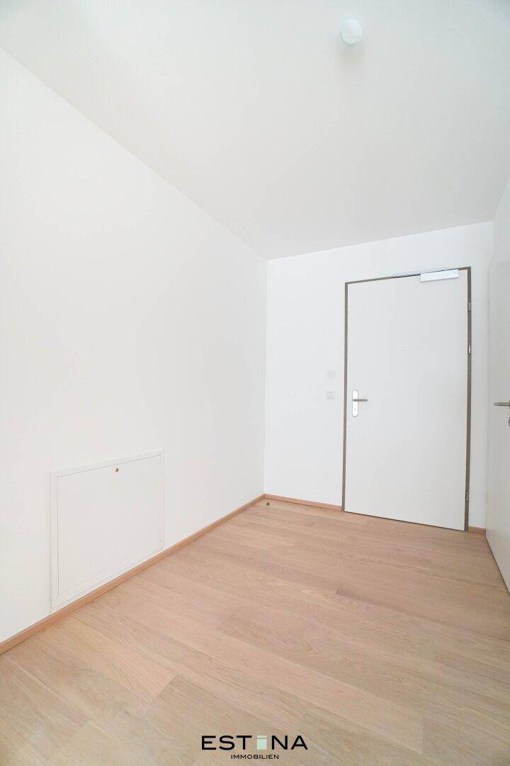 Schmaler Flur mit hellem Parkettboden und weiß gestrichenen Wänden, bereit zum Einzug.