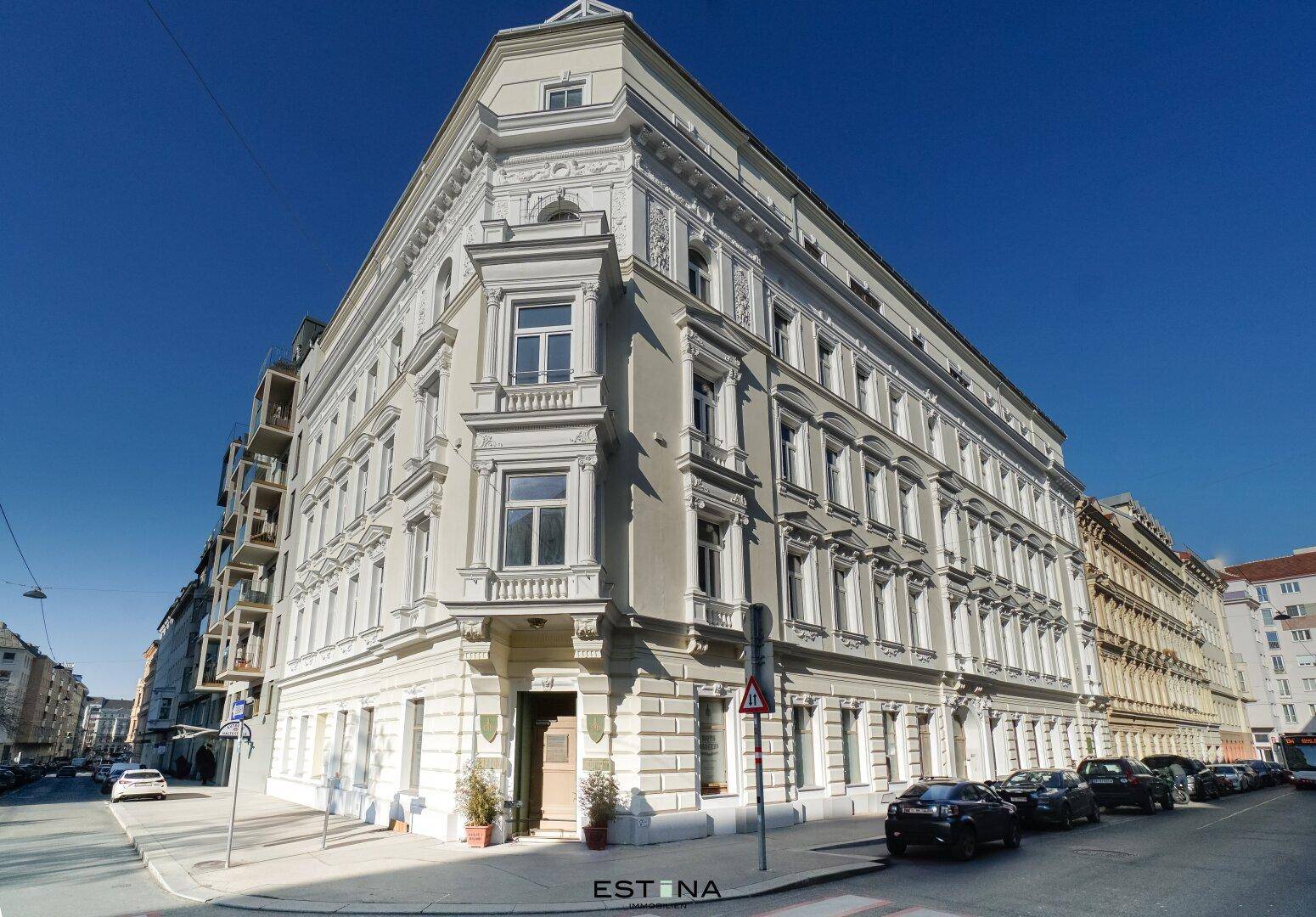 Historisches Eckgebäude mit klassischer Architektur und vielen Fenstern an einer städtischen Straße.