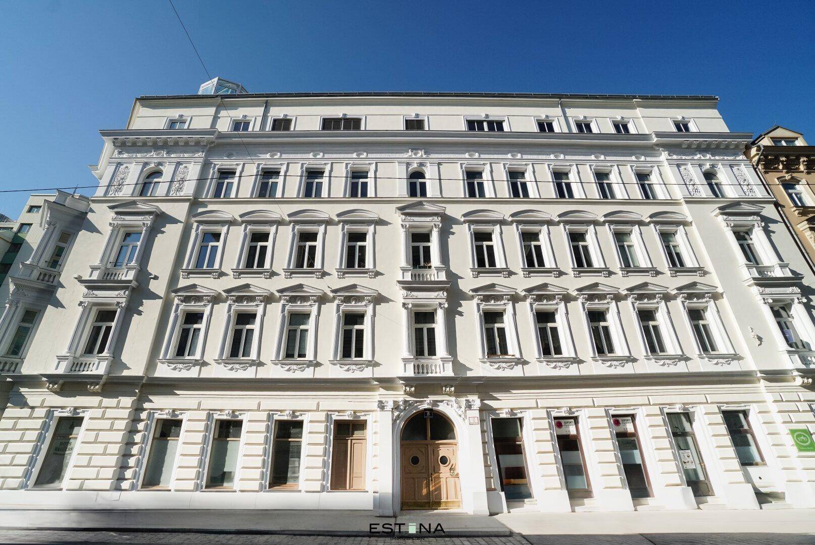 Klassische Fassade eines Mehrfamilienhauses mit vielen Fenstern und einem großen Holztor.