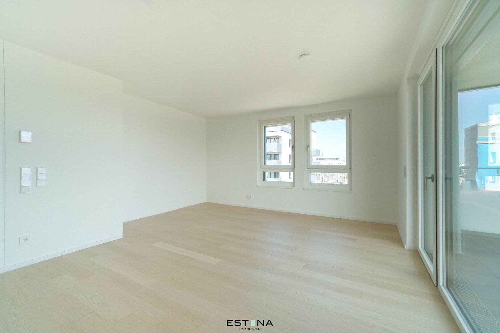 Geräumiges, helles Zimmer mit Holzboden und großen Fenstern, bietet viel Tageslicht.