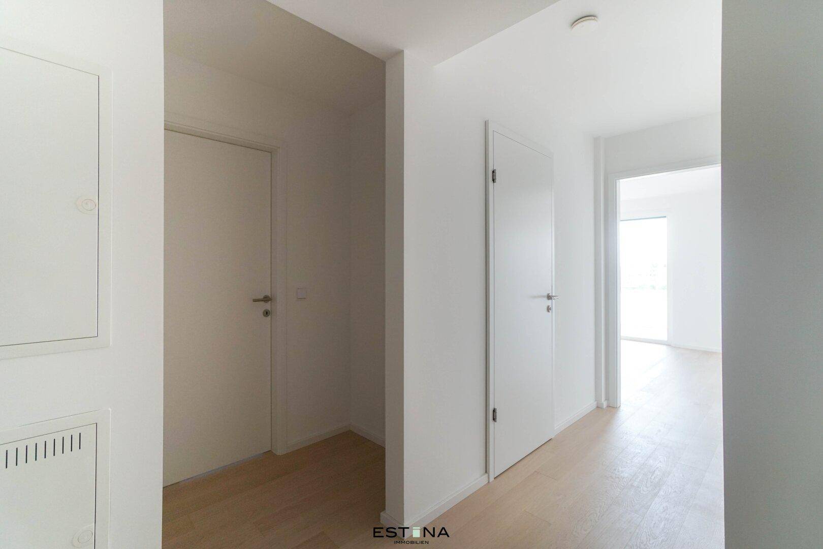 Heller Flur mit Holzboden und mehreren Türen, verbindet die verschiedenen Wohnbereiche.