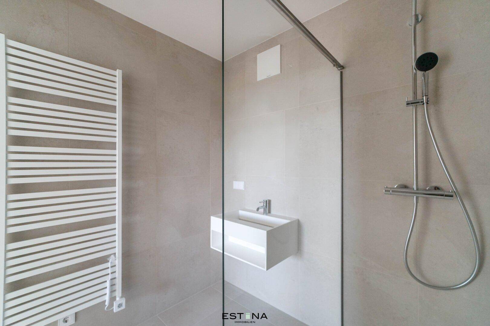 Elegantes Badezimmer mit beheiztem Handtuchhalter, modernem Waschbecken und großer begehbarer Dusche.