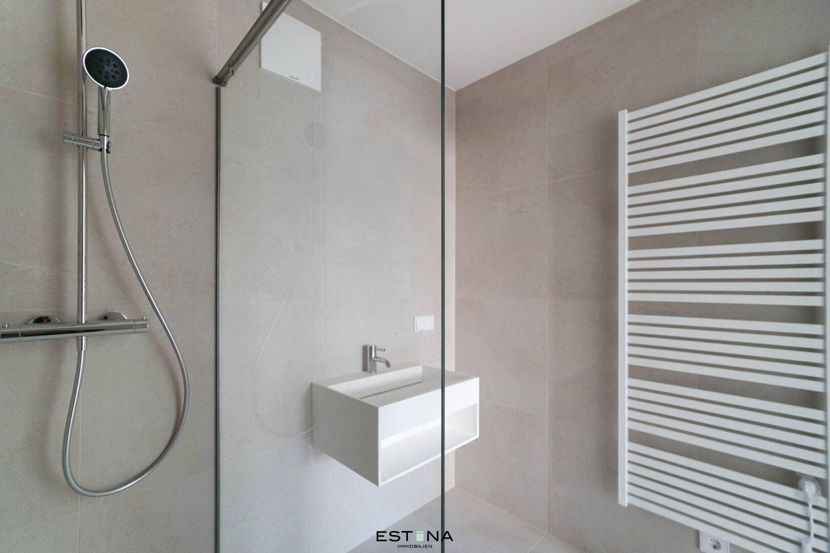 Modernes Badezimmer mit begehbarer Dusche, schwebendem Waschbecken und einem praktischen Handtuchheizkörper.