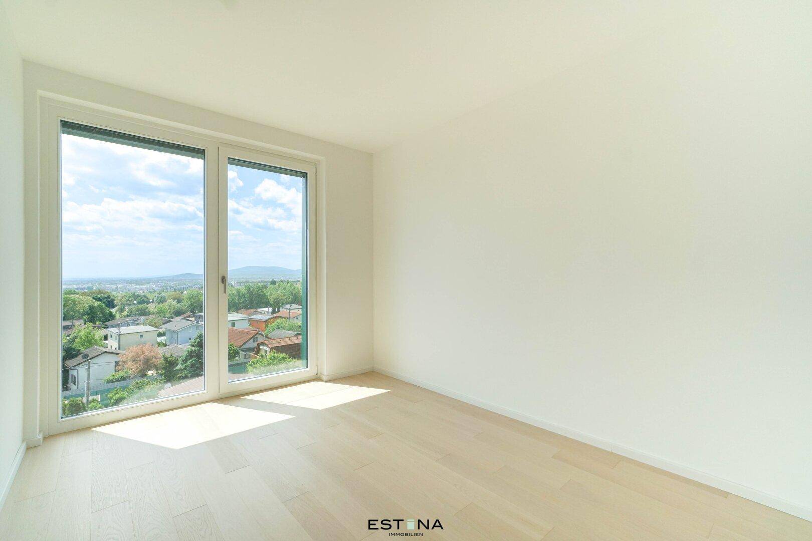 Heller, leerer Raum mit Parkettboden und großen Fenstern, die einen weiten Blick bieten.
