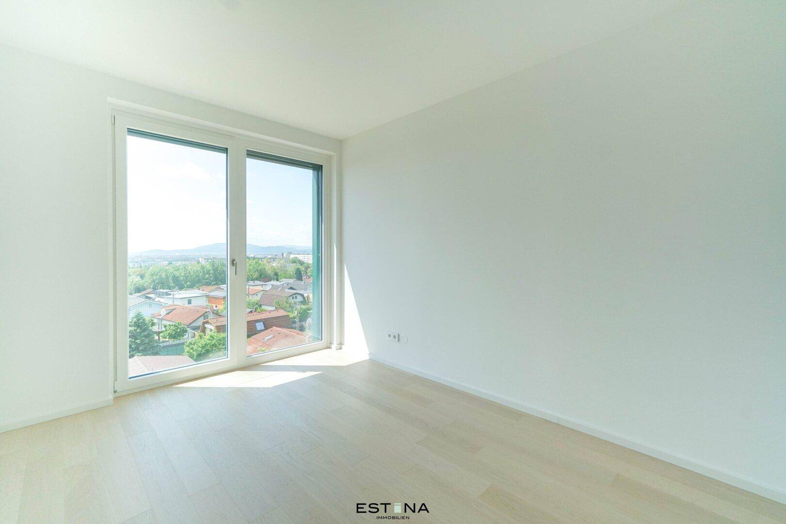 Lichtdurchflutetes Zimmer mit großem Fenster und Blick ins Grüne, ideal als Schlafzimmer oder Büro.