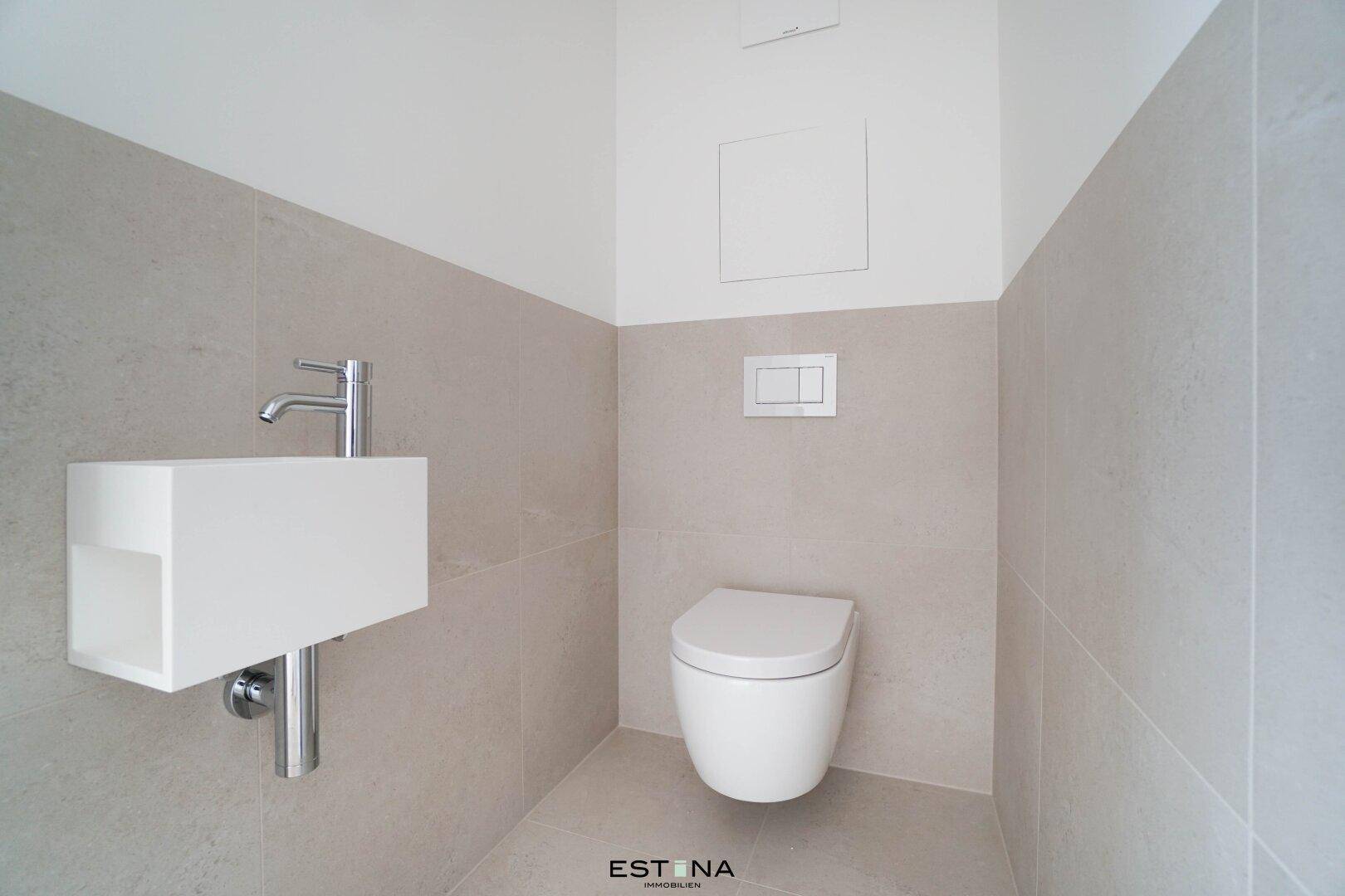 Modernes Gäste-WC mit wandhängender Toilette und kleinem Waschbecken, in hellen Farben gehalten.