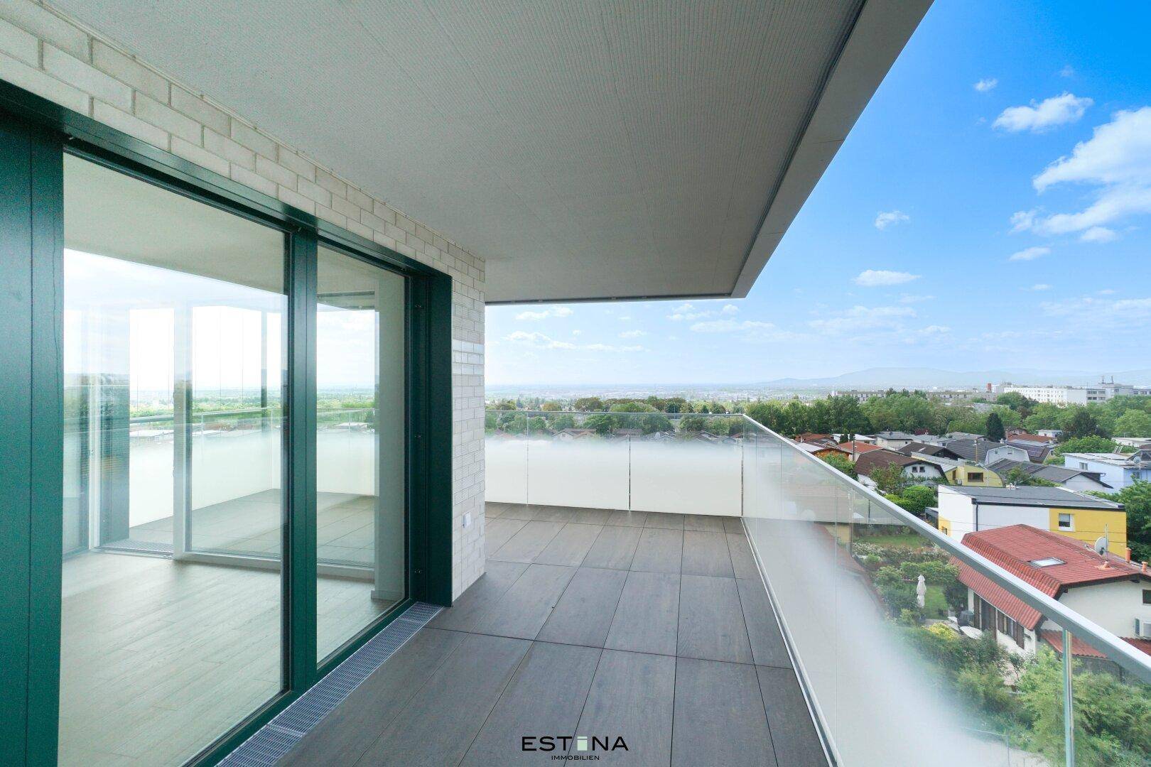 Großer Balkon mit Glasgeländer und weitem Blick über die Stadt und die umliegende Landschaft.