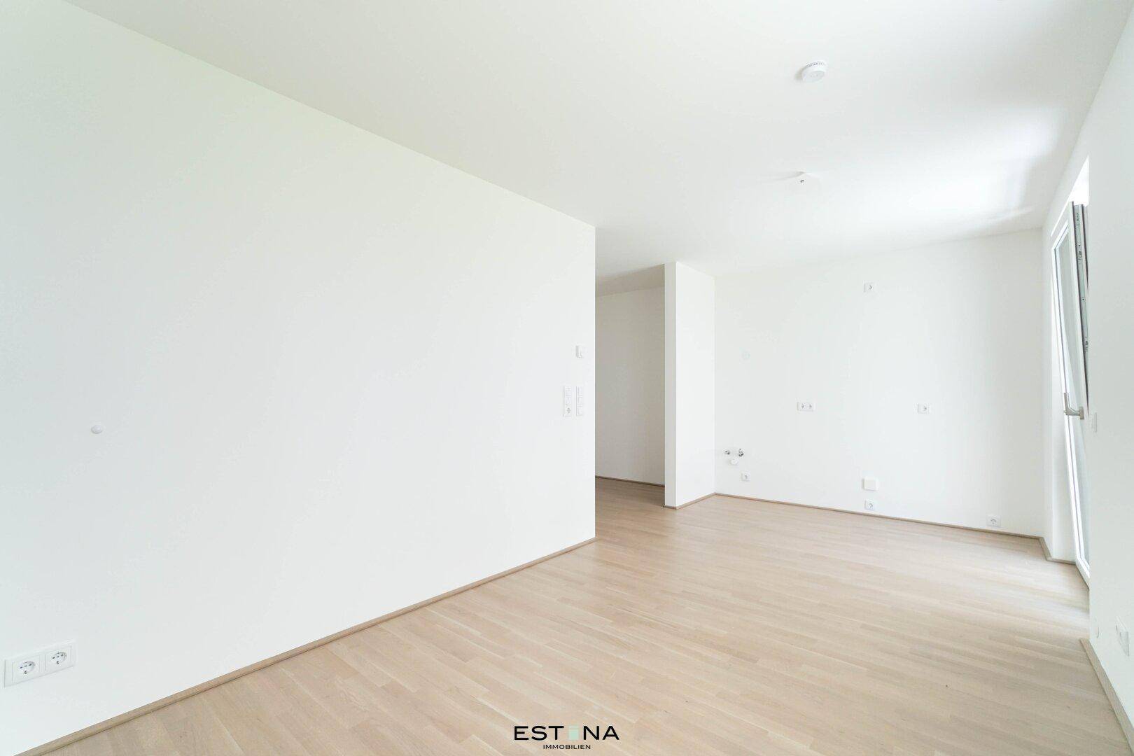 Weitläufiger, unmöblierter Wohnbereich mit hellen Wänden und modernem Holzfußboden.