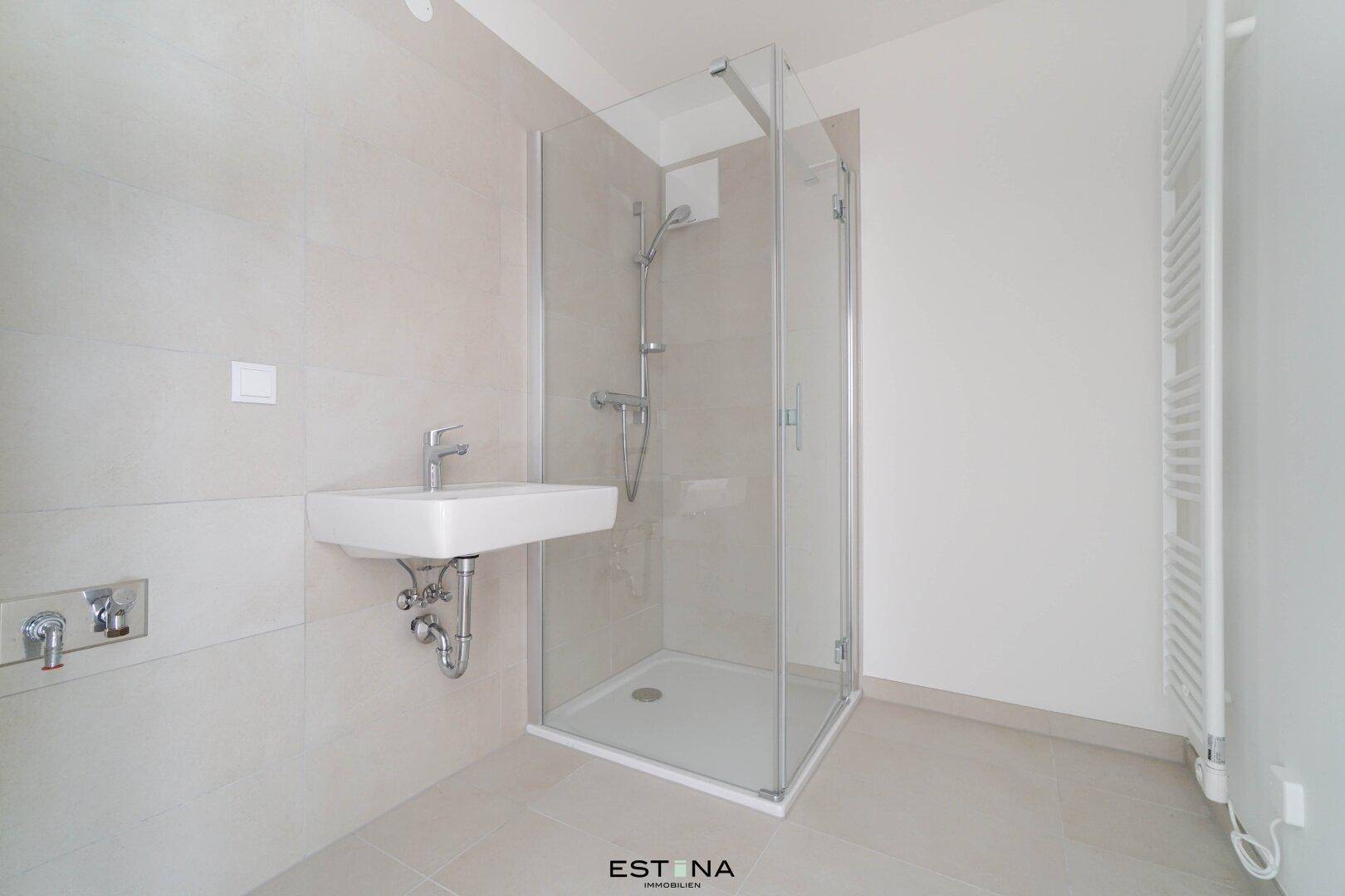 Modernes Badezimmer mit Duschkabine, Wandwaschbecken und hellen Fliesen.
